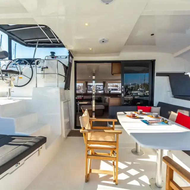 Shaded cockpit of the Lagoon 42 with a large dining table and cushioned seating